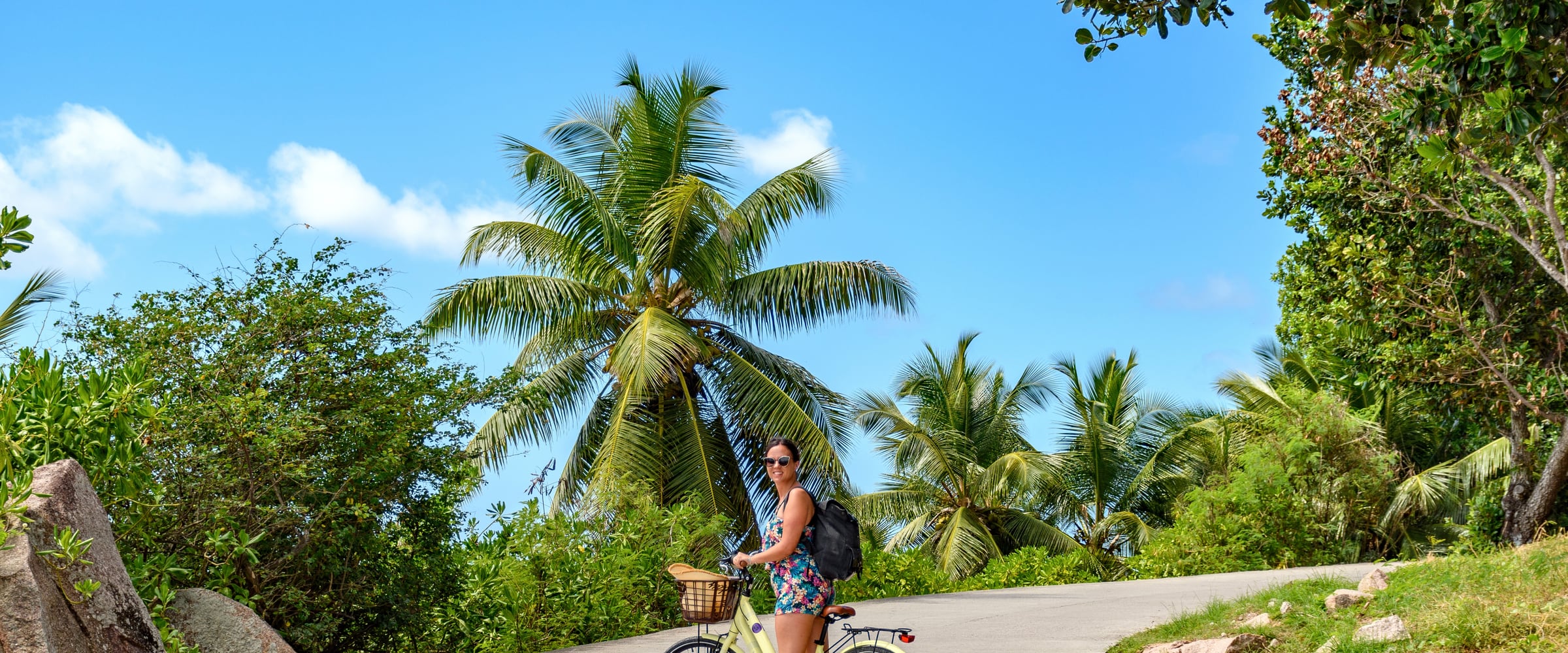 Une cycliste sur une route bordée de cocotiers